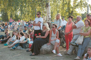 Atėję į koncertą Poezijos parke žmonės įsitaiso kaip kam patogiau... 