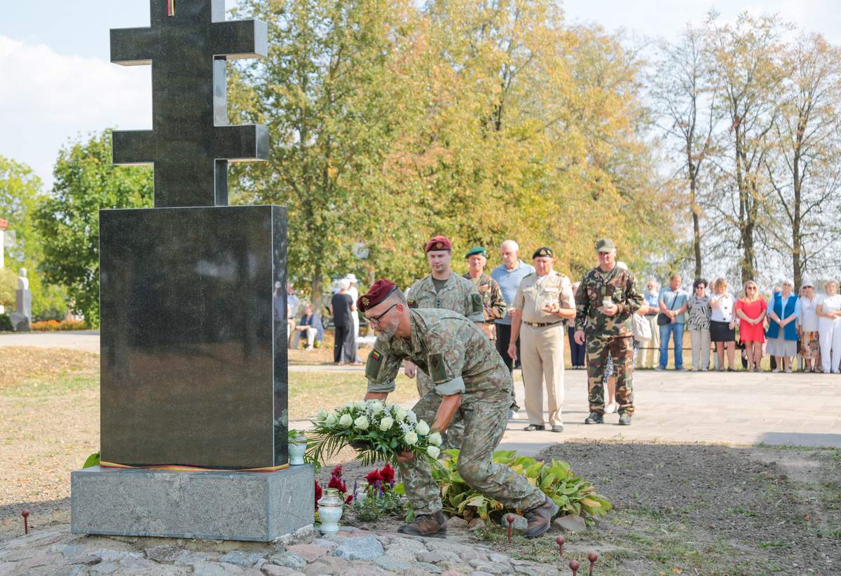Prie paminklo padėta gėlių, uždegtos žvakės.