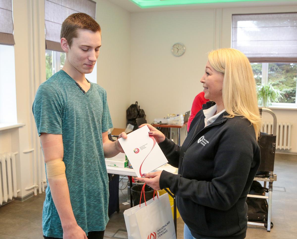 Savanorė Vaida Degutytė pirmą kartą kraujo davusiam studentui Rokui Juodsnukiui įteikė specialų pažymėjimą.