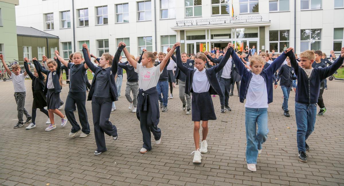 Pilnas mokyklos kiemas šokančių moksleivių.